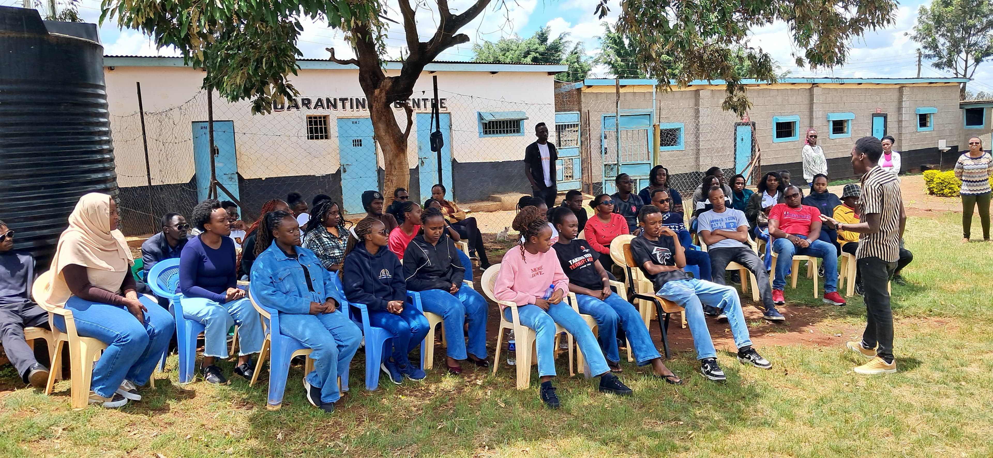 A mentor sitting with young people around a table, reviewing papers together.