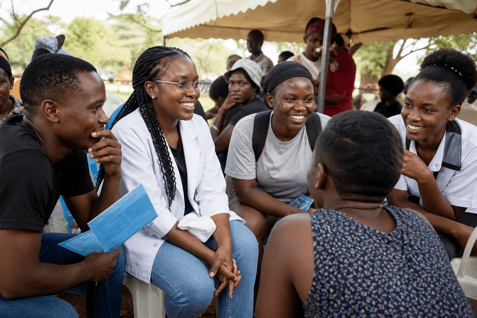 Young people and health professionals talking together at an outdoor wellness gathering.